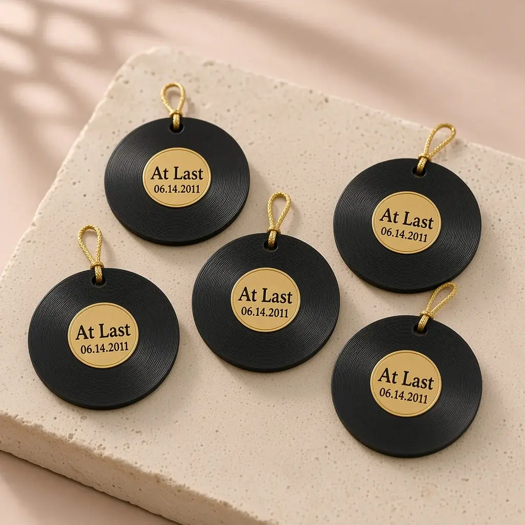 Small black record medallions with gold labels reading At Last and a date, with gold cords.