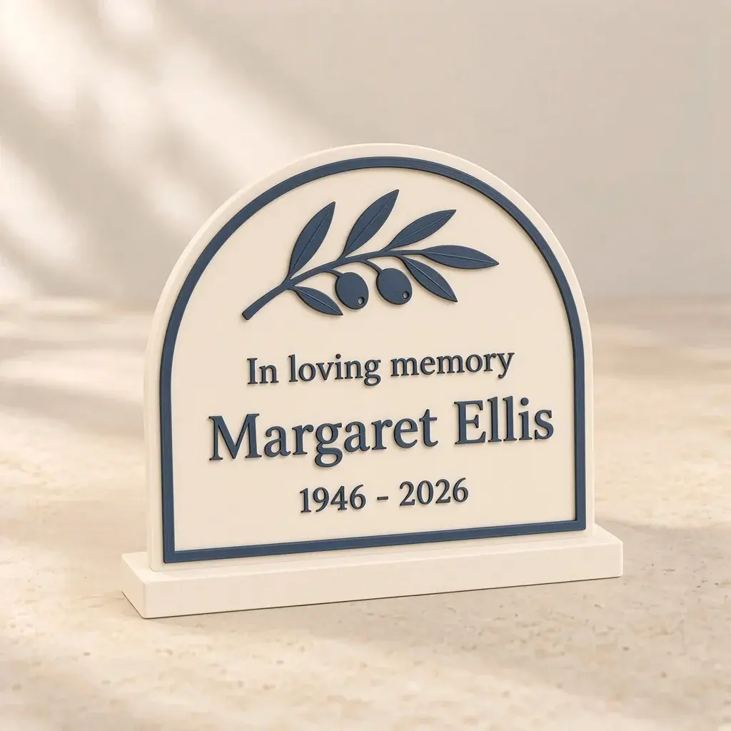 Ivory arch-top memorial plaque with a slate-blue border, an olive branch and the name Margaret Ellis.