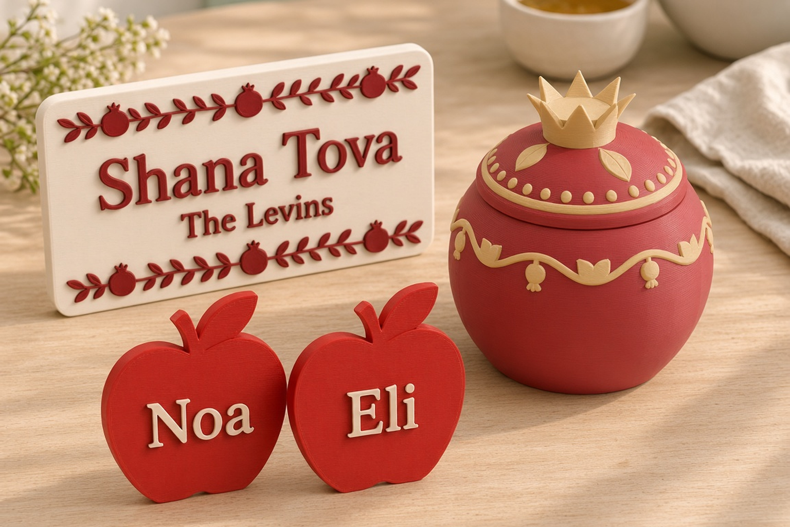 Rosh Hashanah collection with a deep red pomegranate box with a gold crown, an ivory Shana Tova plaque and red apple place names