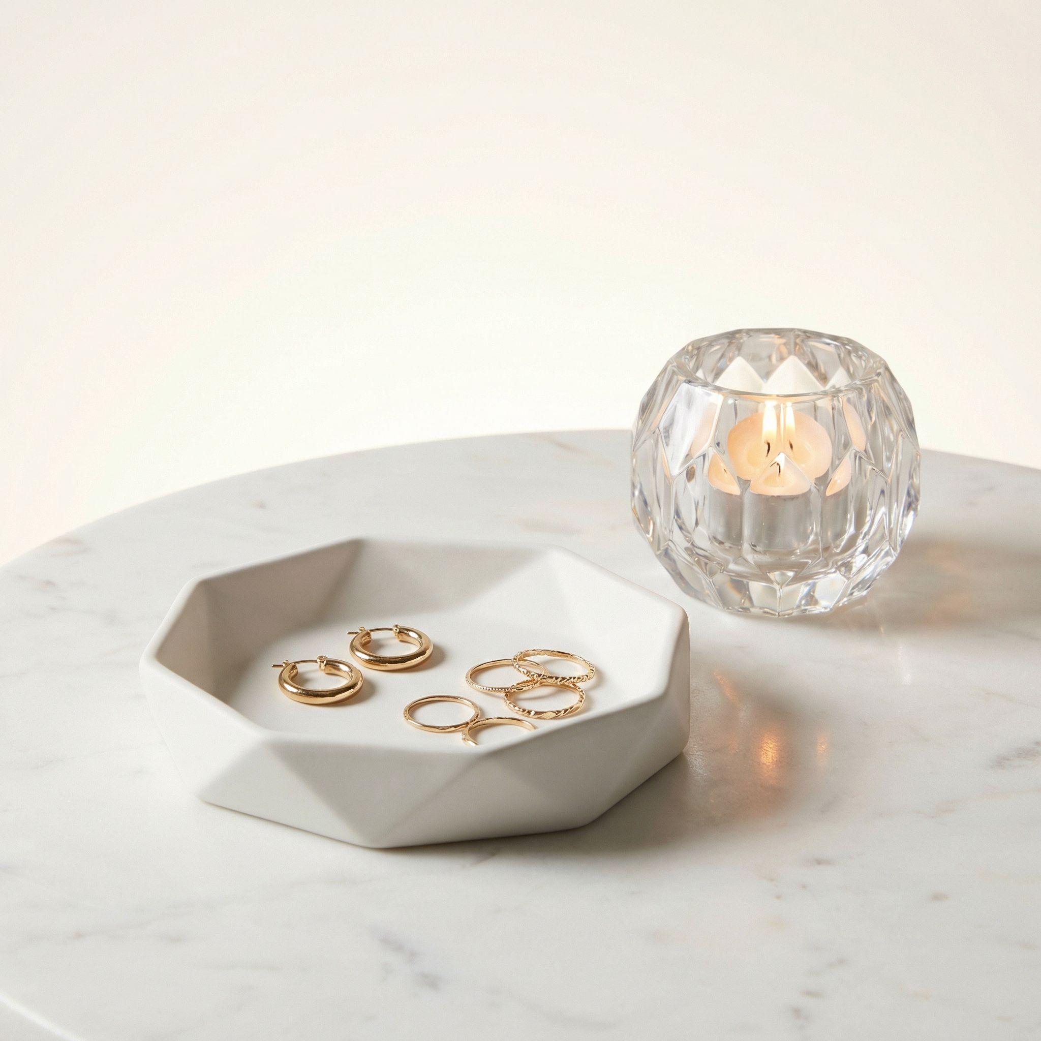 Decor inspiration: a faceted ivory tray with jewelry beside a glass candle holder